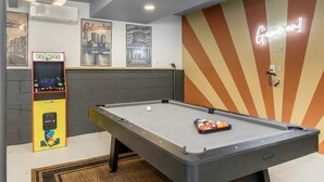 A pool table with a neon sign, a Pac-Man arcade machine, and cityscape artwork on the wall. - Pool, Hot tub and Gameroom! (Columbus)