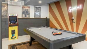 Ein Billardtisch, ein Pac-Man-Spielautomat und Stadtansichten an der Wand.