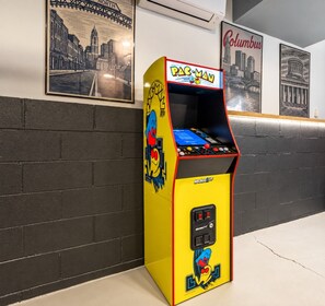 A Pac-Man arcade machine in a hallway with brick walls and framed cityscape pictures on the wall. - Pool, Hot tub and Gameroom! (Columbus)