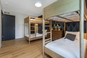 Ein Zimmer mit zwei Etagenbetten, einer Holzkommode und einer Wand mit Muster.