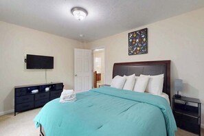 Ein Schlafzimmer mit einem Bett, einem Flachbildfernseher, einem Schminktisch und einem Nachttisch.