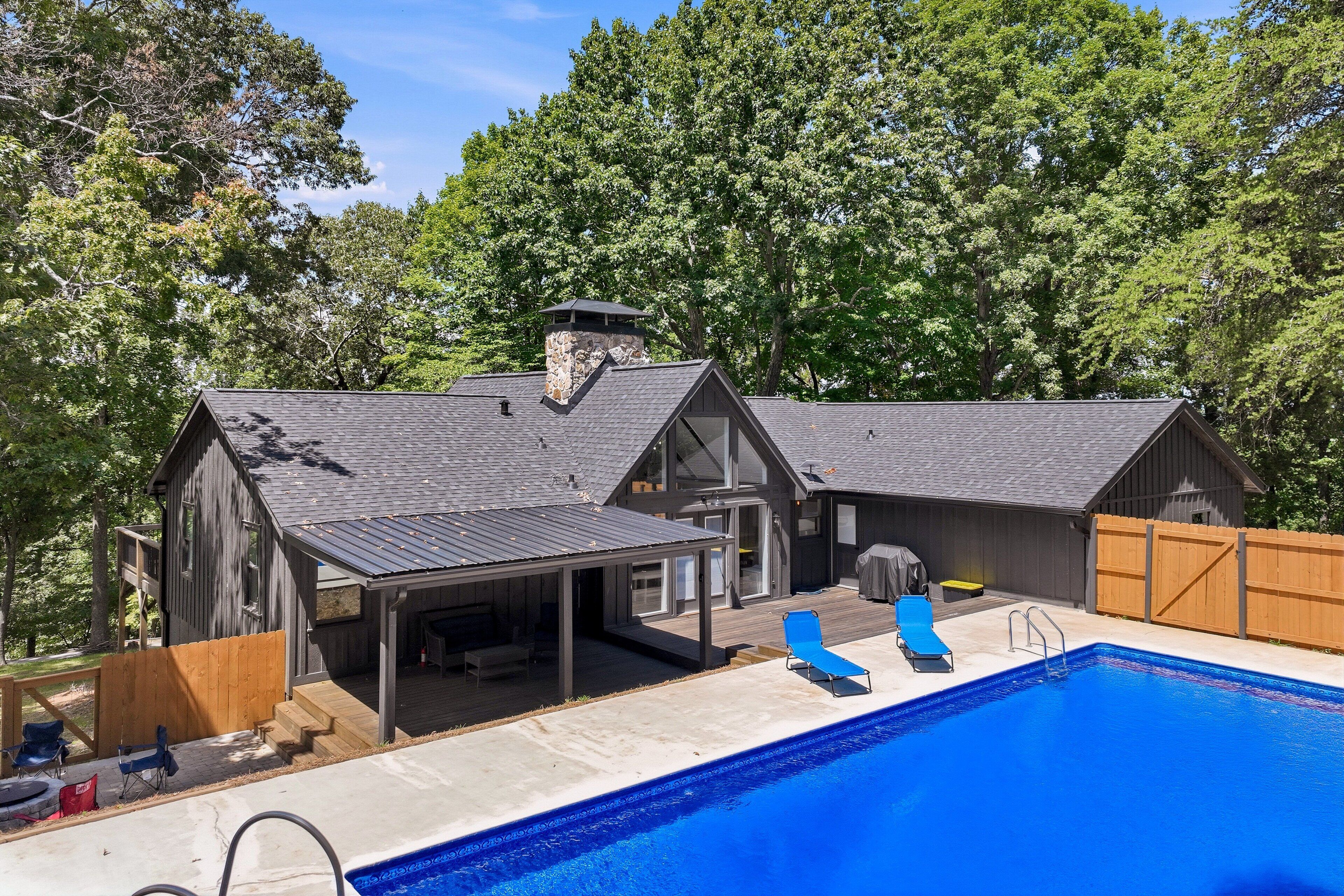 Une propriété résidentielle dotée d’une piscine, d’un patio couvert et d’une terrasse en bois.