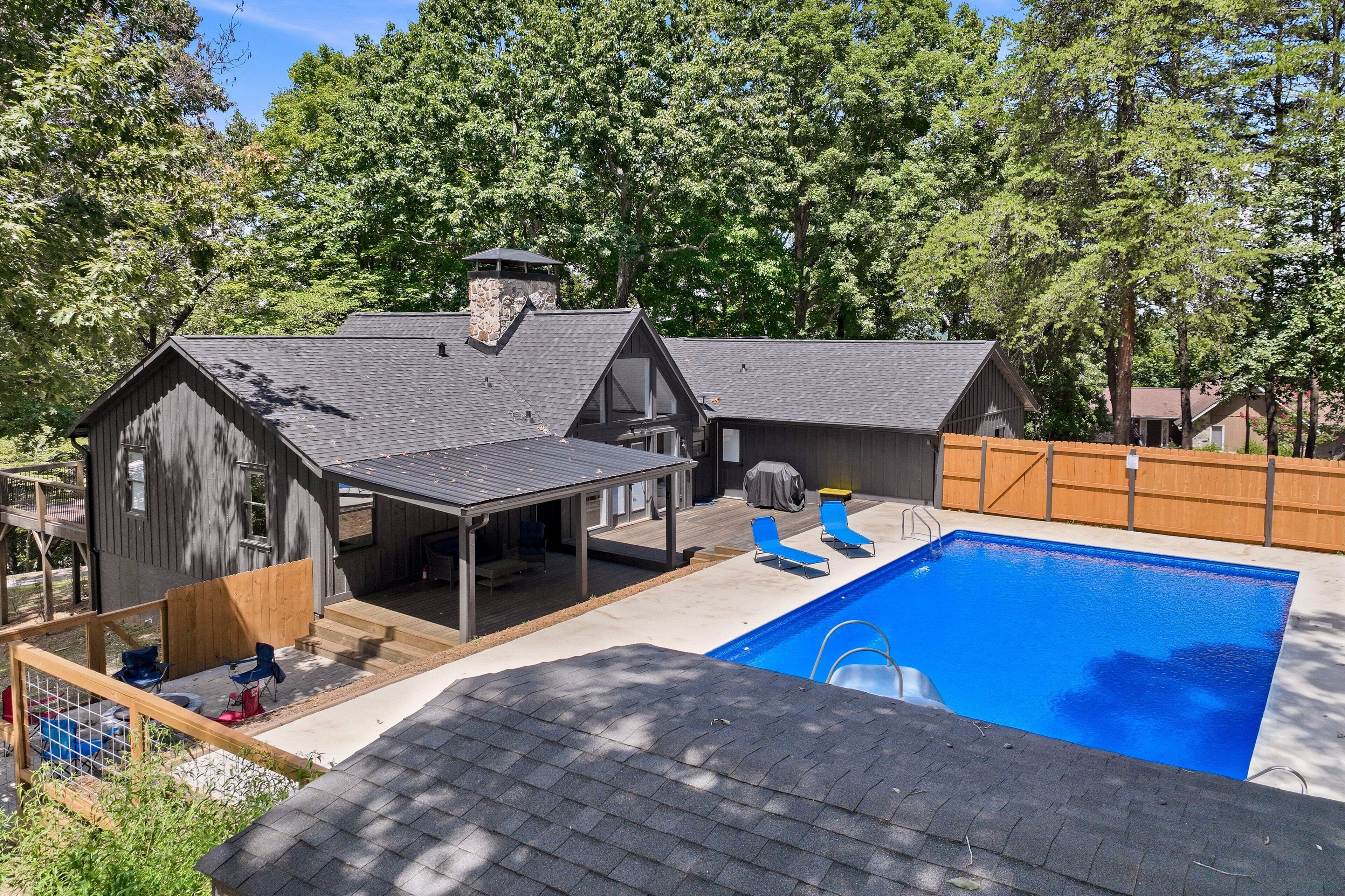 A residential property with a swimming pool, a covered patio, and a wooden deck.