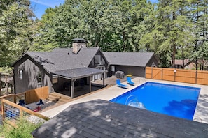 Ein Wohnhaus mit Swimmingpool, überdachter Terrasse und Holzdeck.