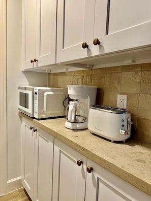 Eine Küche mit weißen Schränken, einer Mikrowelle, einer Kaffeemaschine und einem Toaster auf der Arbeitsfläche.