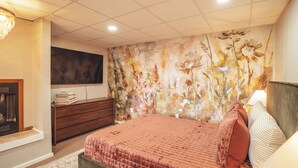 Ein Schlafzimmer mit Bett, Kommode und einem an der Wand befestigten Fernseher.