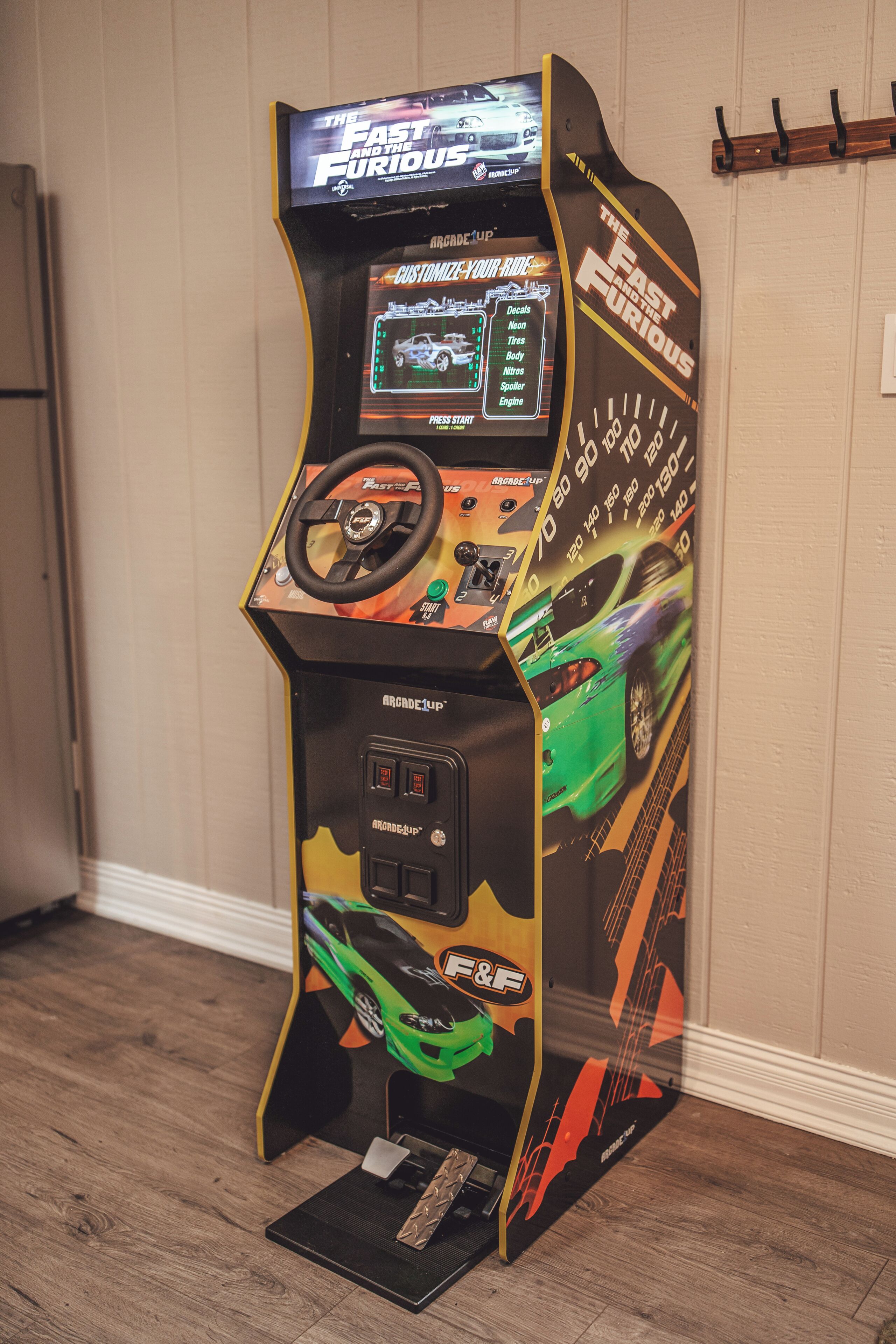 Eine Rennspiel-Arcade-Maschine mit Lenkrad, digitalem Display und Geschwindigkeitsmesser.