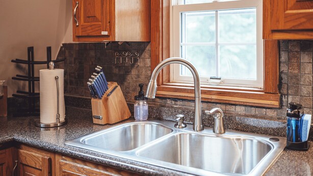 A kitchen with a double stainless steel sink, wooden cabinets, a window, and a knife block. - Easy access/Hot tub/Fire pit/play set/Arcade (Rockbridge)