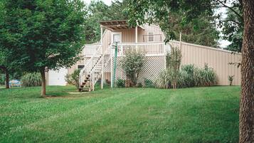 A two-story house with a wooden deck and a fenced yard.