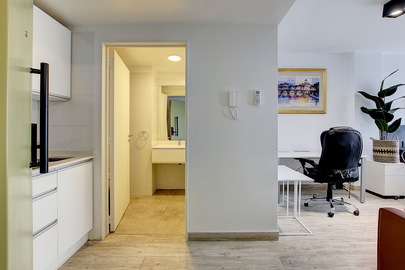 A modern kitchen with white cabinets, a black countertop, and a wooden floor.