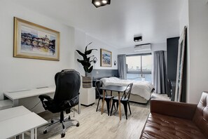 A hotel room with a bed, desk, chair, and a view of the city. - Premium Studio | Corrientes Ave, Buenos Aires, Argentina | Coworking Space, Gym & Rooftop BBQ (Buenos Aires)