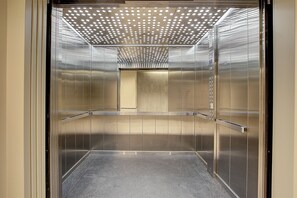 An empty elevator with metallic walls and a reflective ceiling. - Premium Studio | Corrientes Ave, Buenos Aires, Argentina | Coworking Space, Gym & Rooftop BBQ (Buenos Aires)