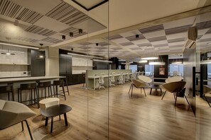 A modern office space with a bar area, multiple seating arrangements, and a view of the outside through large windows. - Premium Studio | Corrientes Ave, Buenos Aires, Argentina | Coworking Space, Gym & Rooftop BBQ (Buenos Aires)