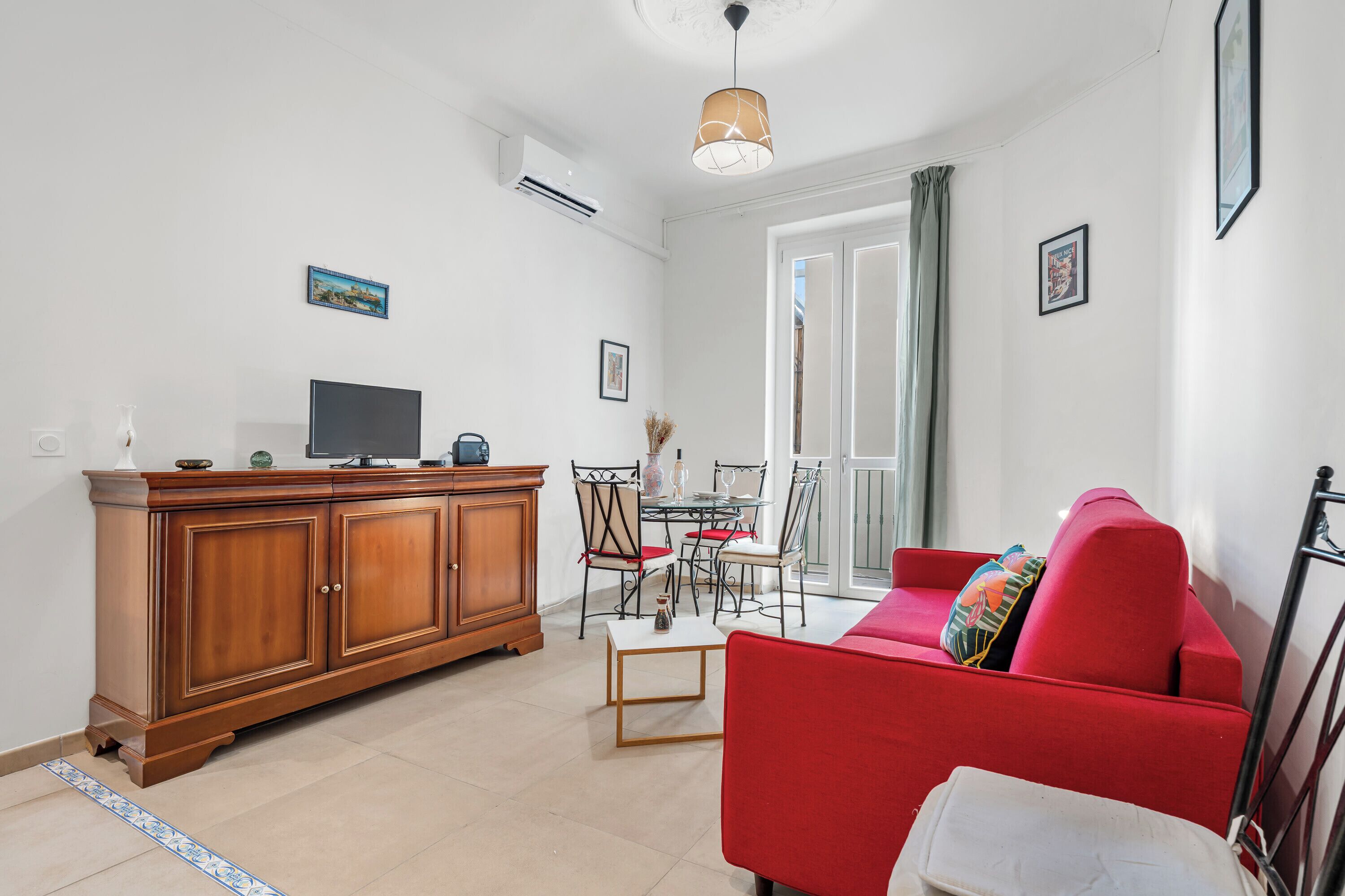 A living room with a red sofa, wooden cabinet, and a television.