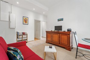 Een woonkamer met een rode bank, een houten kast, een televisie en een boekenkast.