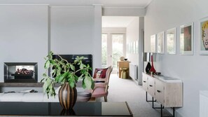 Un salon moderne avec une cheminée, un téléviseur, un canapé, une table basse et un meuble.