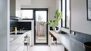 Eine moderne Küche mit schwarzem Fliesenrückwand, Edelstahlgeräten und einem großen Fenster.