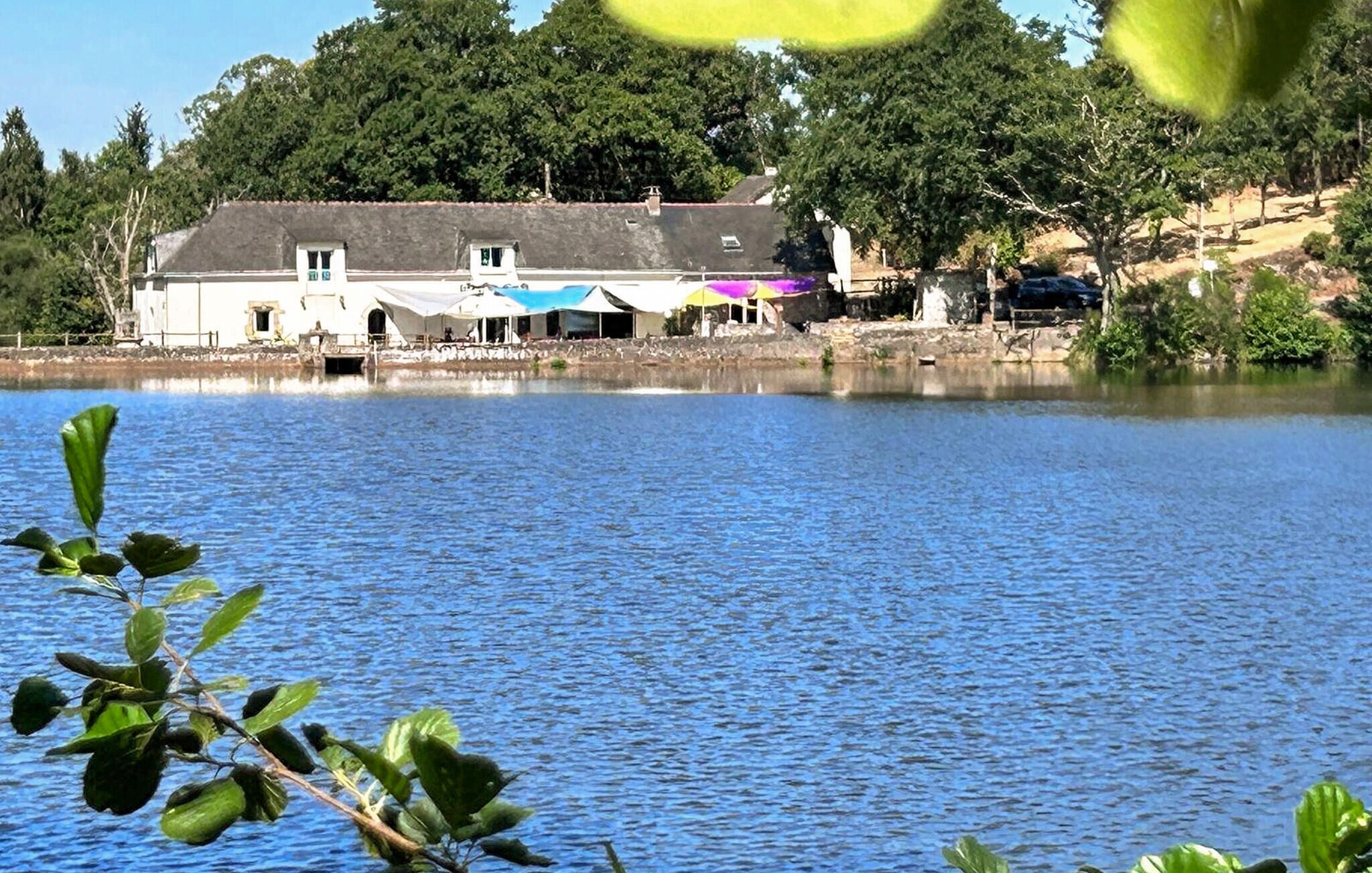 Un bâtiment situé au bord d ’un lac, doté d’un quai, entouré d’arbres et bordé par une étendue d’eau calme.
