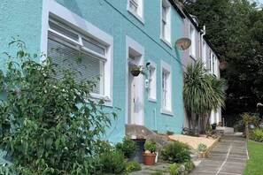 A two-story building with a light blue exterior, white window frames, and a stone staircase leading to the entrance. - Largo Bay - Harbour Hideaway (Leven)