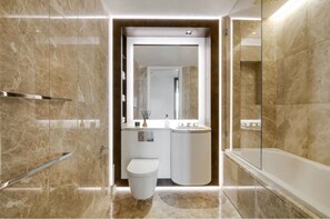 A modern bathroom with a marble floor, a toilet, a sink, and a bathtub. - Luxury London Apartment with 3 Bedrooms (London)