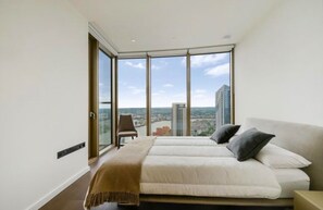 A bedroom with a large bed, a chair, and a view of a cityscape through floor-to-ceiling windows. - Luxury London Apartment with 3 Bedrooms (London)