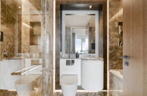A modern bathroom with a glass-enclosed shower, a white sink, and a marble-tiled vanity. - Luxury London Apartment with 3 Bedrooms (London)