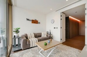 A modern living room with a sofa, a coffee table, and a wall clock. - Luxury London Apartment with 3 Bedrooms (London)