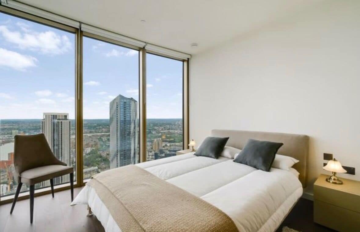 A hotel room with a large bed, a chair, and a nightstand with a lamp.