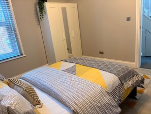 Un dormitorio con cama, armario y ventana con persianas.