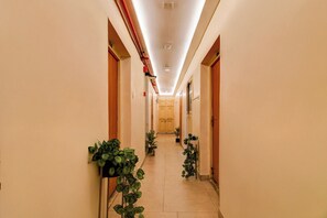 A long, narrow hallway with doors on both sides, leading to a room at the end.