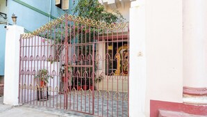 A gated entrance with a decorative iron gate, potted plants, and a building with a white facade. - Collection O Lake Mall Kalighat (Kolkata)