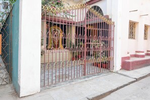 A gated entrance with a decorative iron gate, potted plants, and a small set of steps leading to a building entrance.