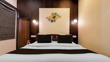 A hotel room with a large bed, two bedside tables, a wall-mounted light fixture, and a decorative wall piece.