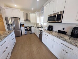 A modern kitchen with white cabinetry, stainless steel appliances, and a granite countertop. - Beautiful Home in Port Antigua with Dock and Private Beach Access (Islamorada)