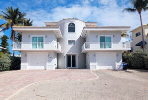 A two-story house with a central entrance, two balconies, and a garage. - Beautiful Home in Port Antigua with Dock and Private Beach Access (Islamorada)