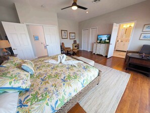 A hotel room with a large bed, a television, a seating area with a chair and a table, and a door leading to a bathroom. - Beautiful Home in Port Antigua with Dock and Private Beach Access (Islamorada)