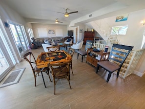 A spacious living area with a dining table, chairs, a staircase, and a view of the outdoors. - Beautiful Home in Port Antigua with Dock and Private Beach Access (Islamorada)