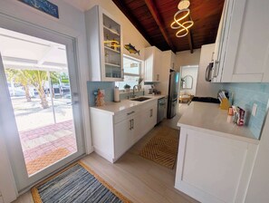 A modern kitchen with white cabinetry, a stainless steel refrigerator, and a tiled backsplash. - Luxury Waterfront Retreat located in Tavernier, FL (Tavernier)