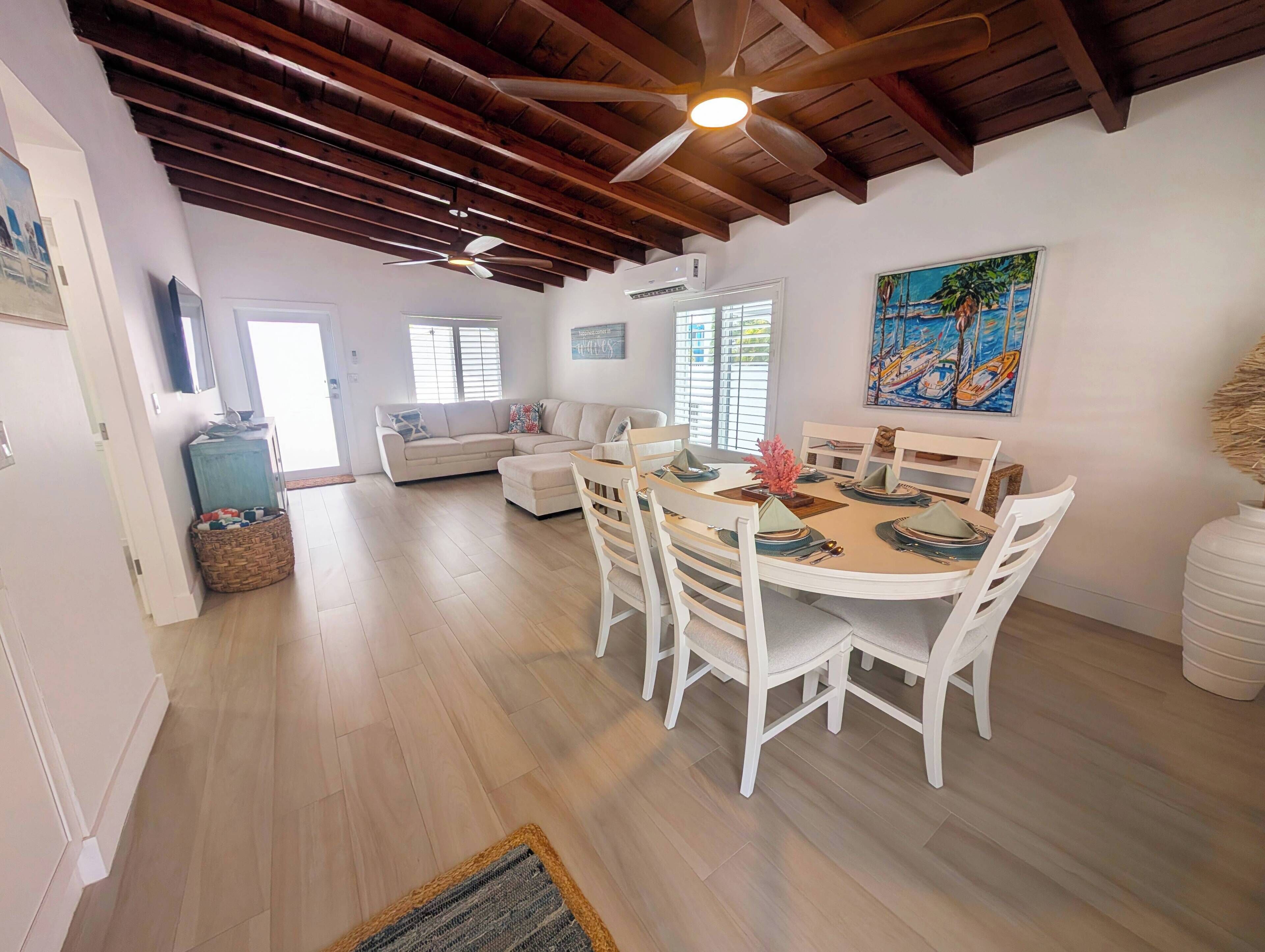 A dining area with a round table, white chairs, and a ceiling fan.