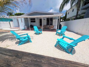 Ein überdachter Außenbereich mit vier blauen Stühlen und einer Holzterrasse.