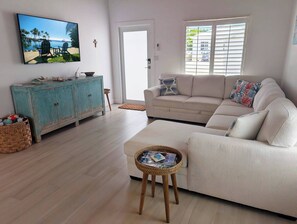 Ein Wohnzimmer mit einer Couch, einem Fernseher, einem Schrank und einem Fenster mit Jalousien.