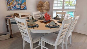 A round dining table with white chairs, set with plates, cutlery, and a centerpiece.