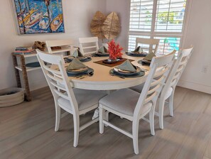A round dining table with white chairs, set with plates, cutlery, and a centerpiece. - Luxury Waterfront Retreat located in Tavernier, FL (Tavernier)