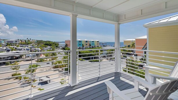A balcony with a view of a beach and parked RVs. - Waterfront 2BR, 2BA Islamorada retreat with pool, hot tub, and kayaks. (Islamorada)