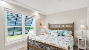 A bedroom with a wooden bed, two bedside tables, a ceiling fan, and a window with blinds. - Waterfront 2BR, 2BA Islamorada retreat with pool, hot tub, and kayaks. (Islamorada)