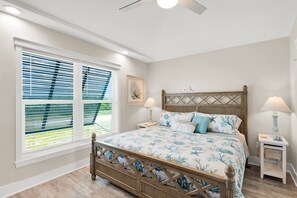 Ein Schlafzimmer mit einem hölzernen Bett, zwei Nachttischen, einem Deckenventilator und einem Fenster mit Jalousien.