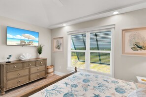 A bedroom with a bed, a dresser, a TV, and a window with blinds. - Waterfront 2BR, 2BA Islamorada retreat with pool, hot tub, and kayaks. (Islamorada)