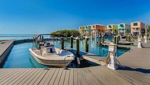 A marina with a docked boat, a wooden walkway, and colorful buildings in the background. - Waterfront 2BR, 2BA Islamorada retreat with pool, hot tub, and kayaks. (Islamorada)