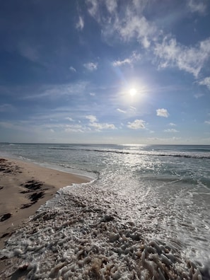 Ein Strand mit Wellen, blauem Himmel und Sonnenschein.