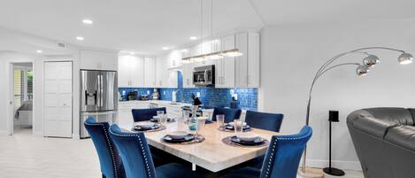 A modern kitchen with white cabinets, a stainless steel refrigerator, and a blue-tiled backsplash.